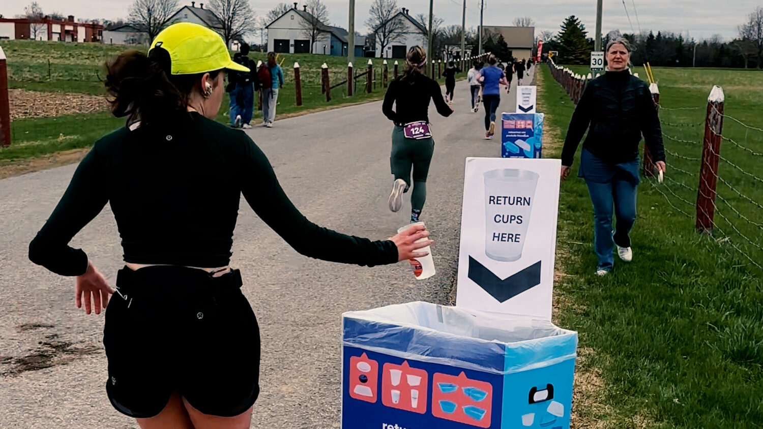 A runner drops a reusable cups into a bin marked "Return cups here". Photo by Craig Conoley/EnviroCentre.